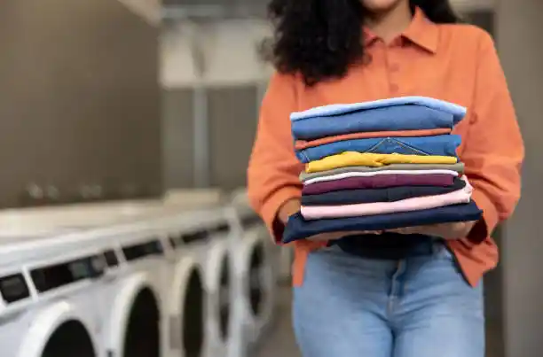Customer holding freshly folded laundry at Lost Sock Laundry drop off laundry service in West Valley City and Magna
